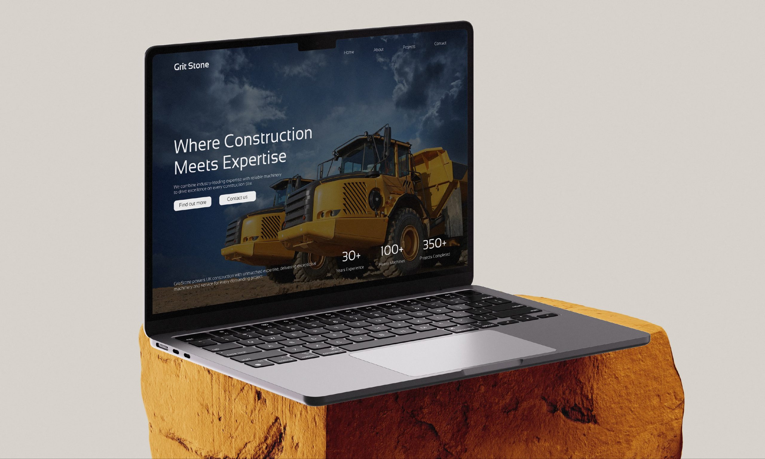 Webpage of Grit Stone showing on a MacBook, sitting on a brown boulder